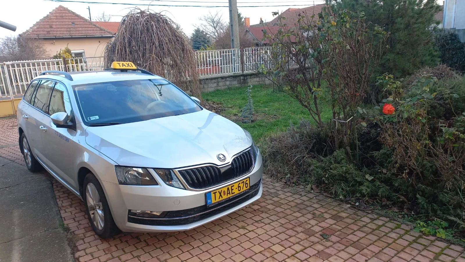 Taxi parkol egy ház előtt, indulásra készen